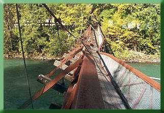 Bridge supported by only one mainline, buckled top chord sections at midspan.  Note upriver mainline draped across bridge and collapsed tower in the distance.