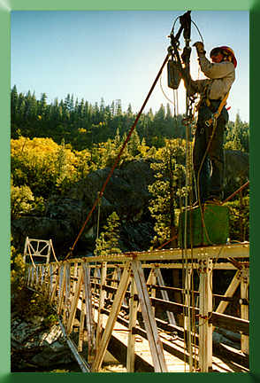 Mack McFarland installing temporary suspenders while standing on sawbuck pannier box.