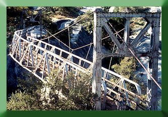 Downriver side; flood damaged bridge showing broken upriver suspenders, deflected mainlines, and  bent truss.