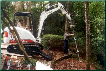 Preparing to install helical pile at location of tower base.