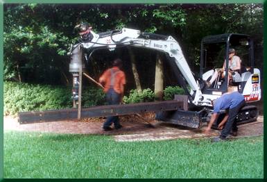 Moving tower leg with excavator over garden paths.